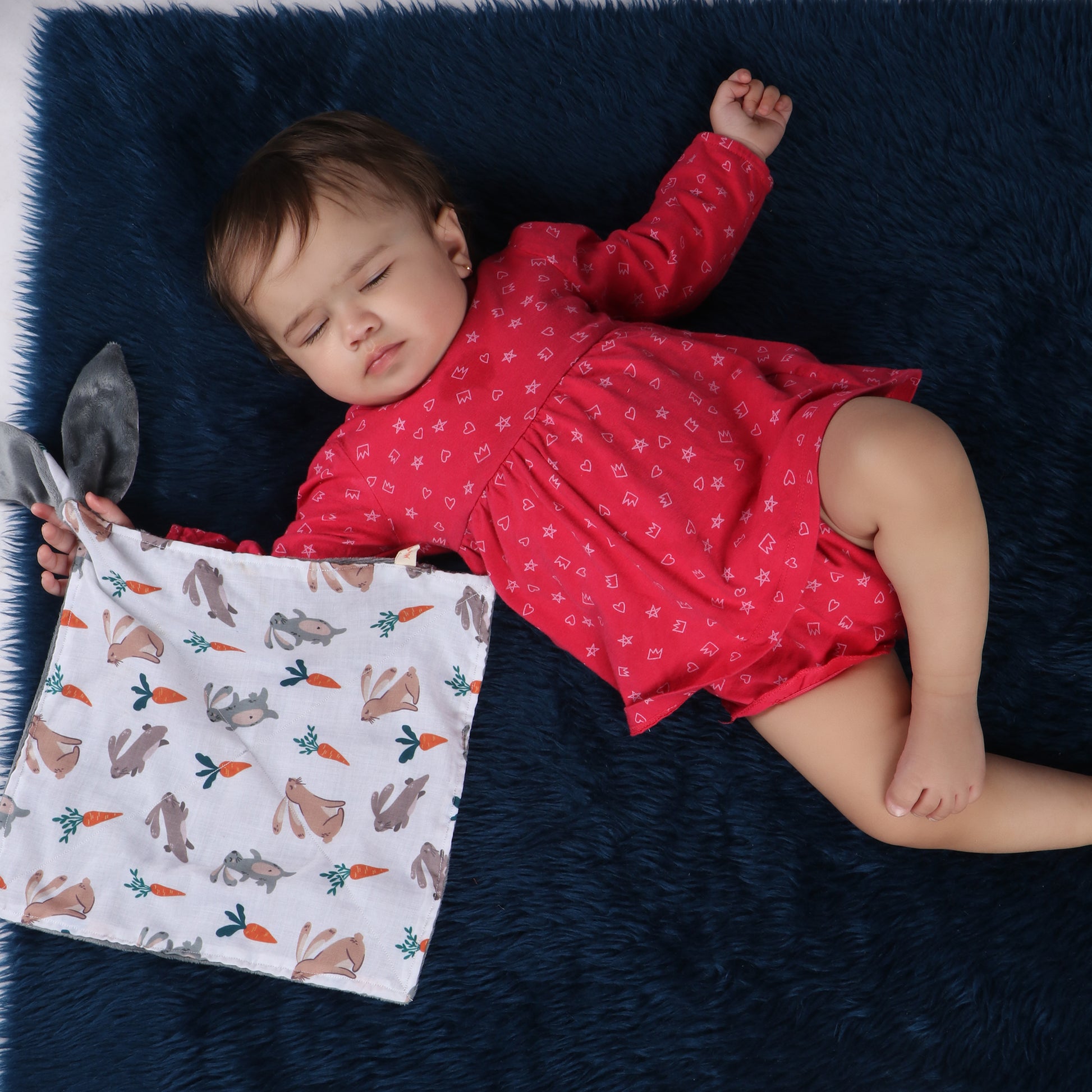 Toddler holding soft security blanket with comforting textures with bunny and carrot print demonstrating its child-friendly size which is perfect for soothing babies and toddlers