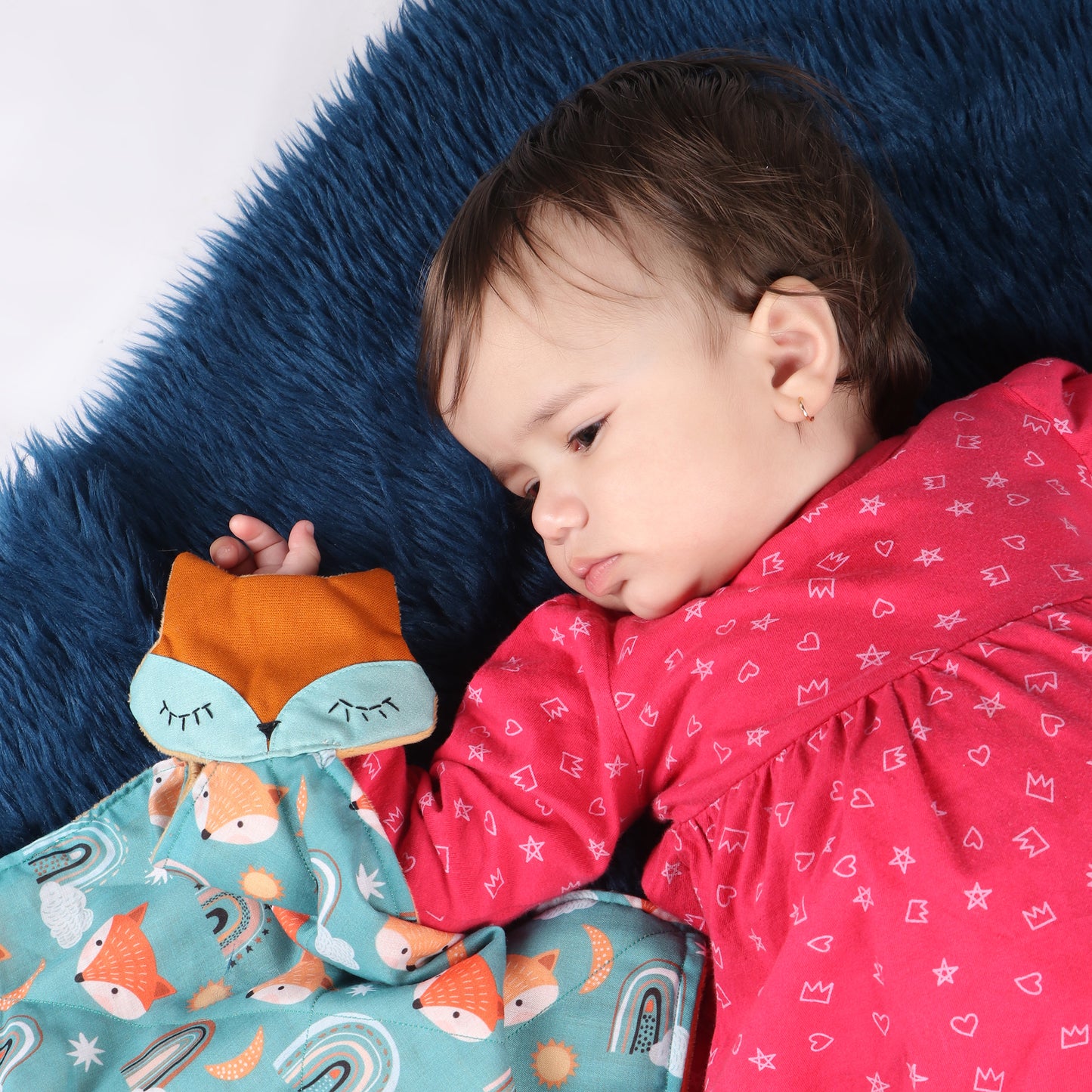 Close up of toddler holding soft security blanket with comforting textures with fox print demonstrating its child-friendly size which is perfect for soothing babies and toddlers