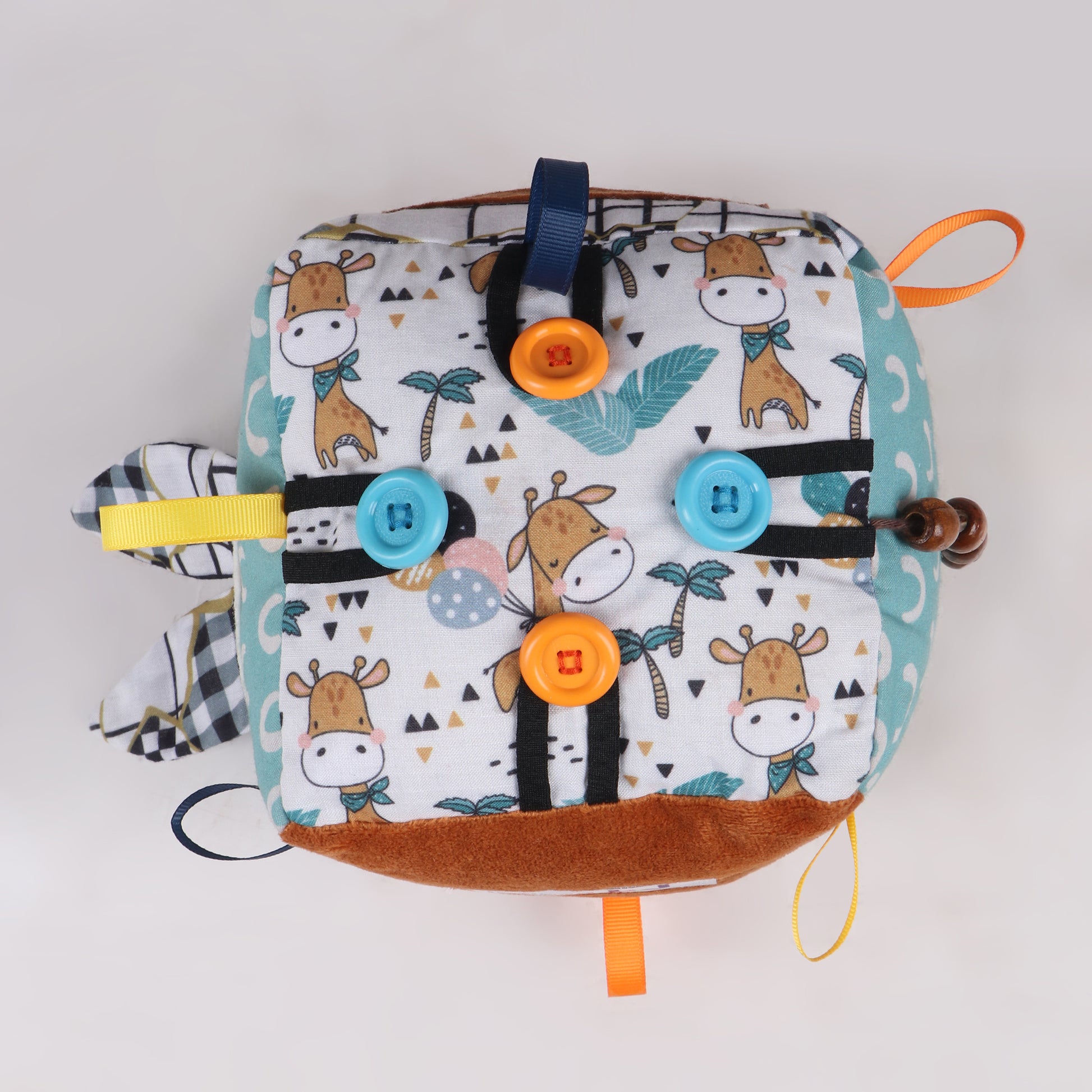 Top view of ribbon and button activity of soft fabric activity cube with interactive elements like ribbons, textures, and buttons for early childhood development