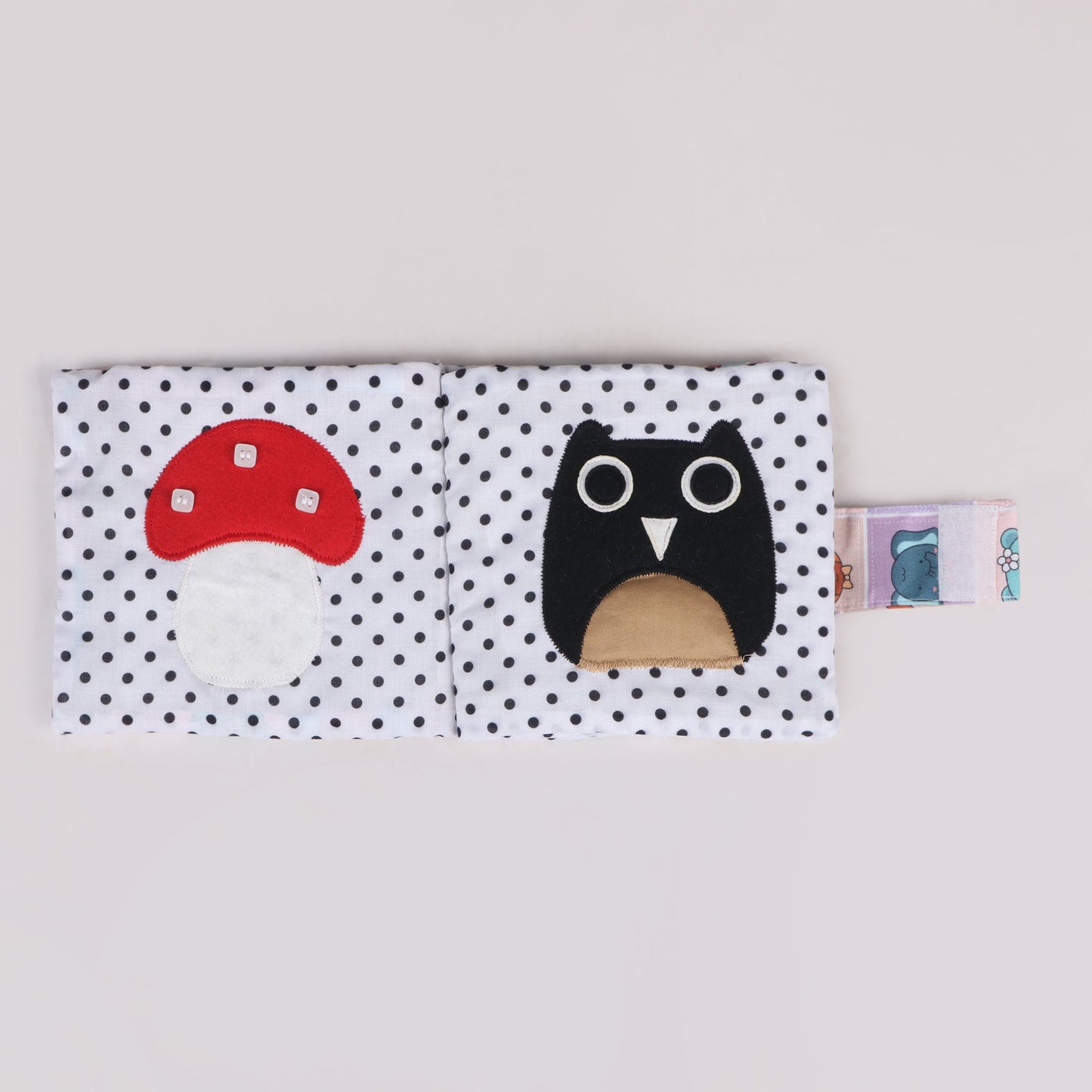Sensory fabric book featuring a mushroom-shaped page with three stitched buttons for tactile exploration and an owl-shaped page designed for a unique sensory feel, enhancing fine motor and sensory skills
