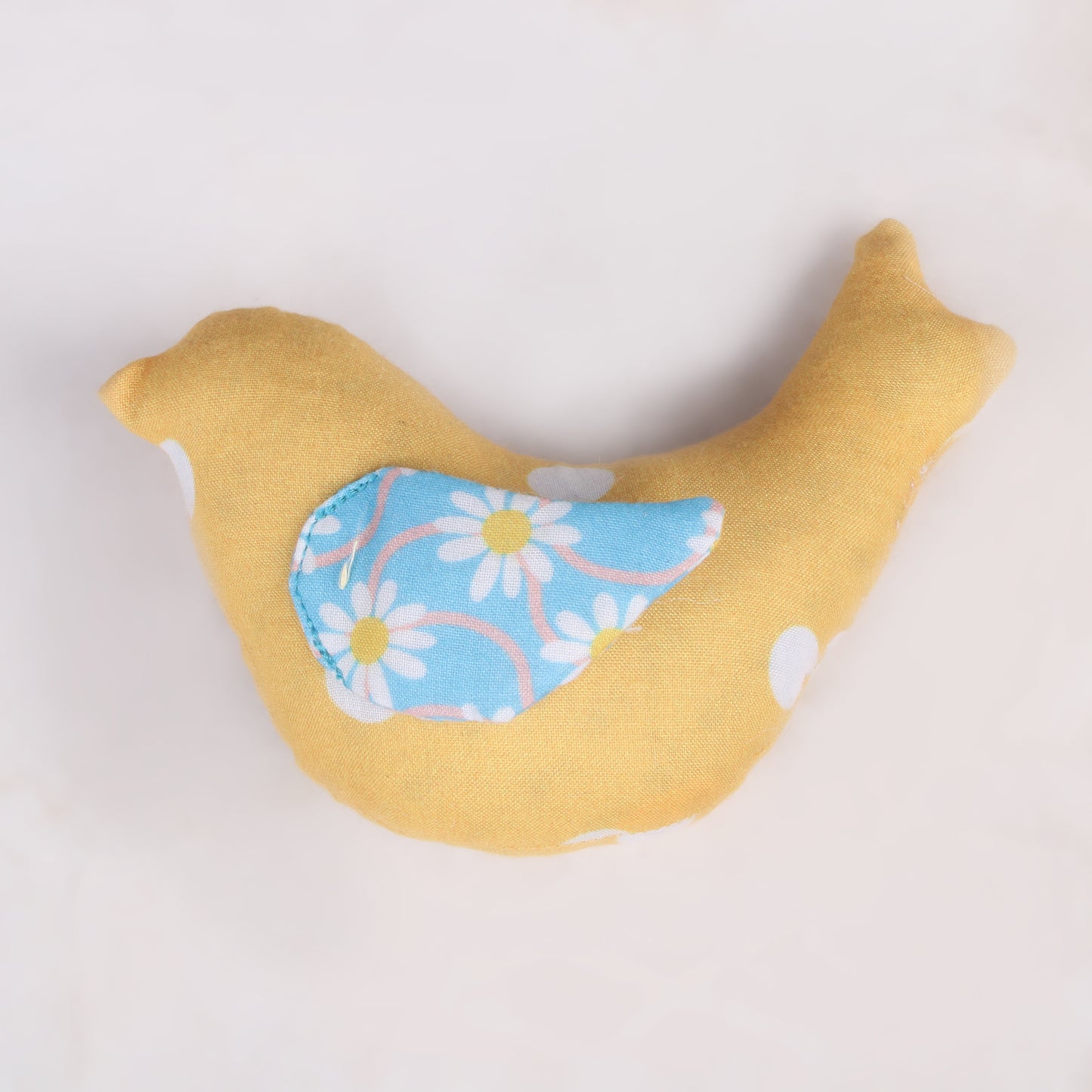 Bird-shaped sensory taggie toy with yellow colored fabric for tactile exploration and comfort