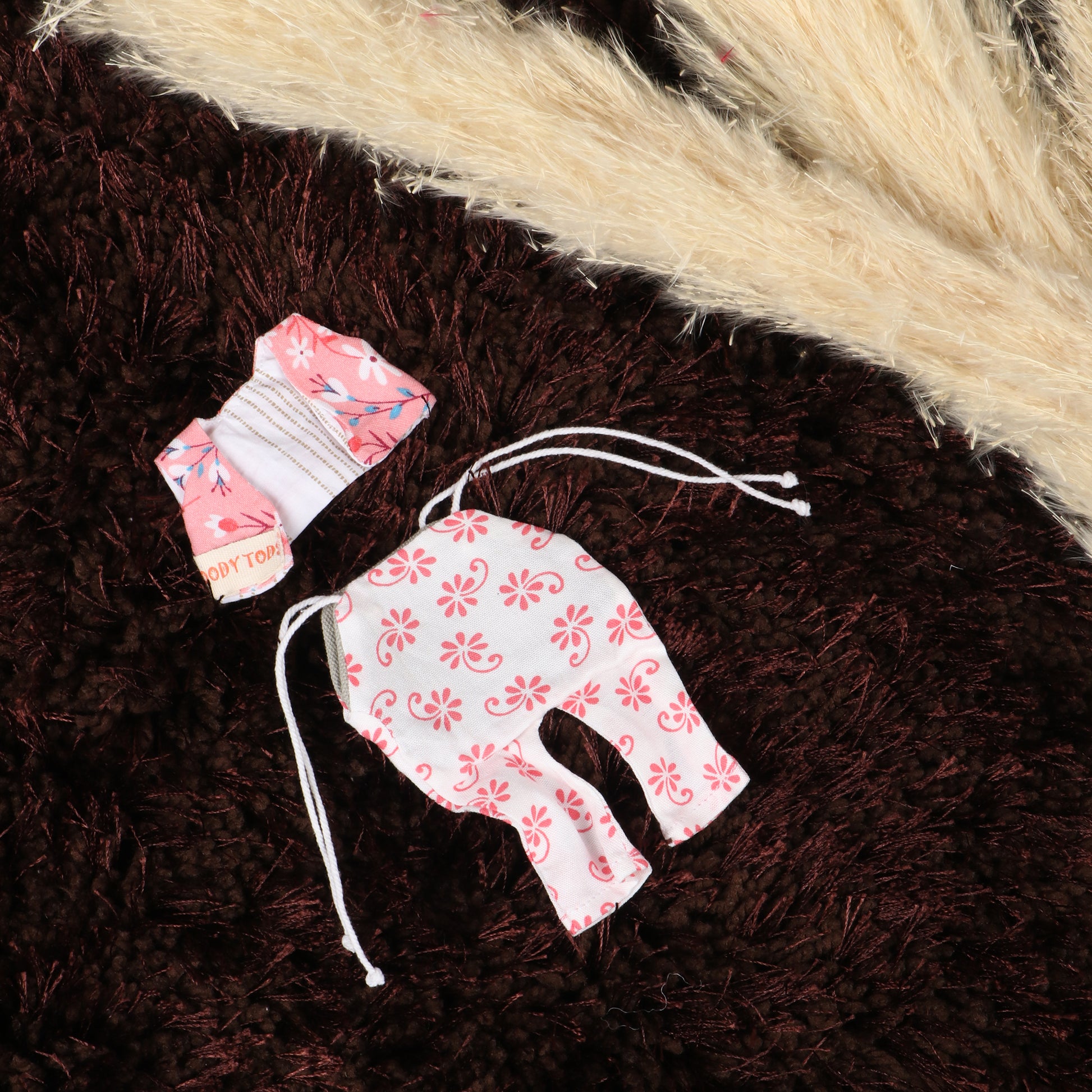 Close up of cute handmade pink dress for 7 inch fabric boy rag doll made from child-safe, soft fabric.
