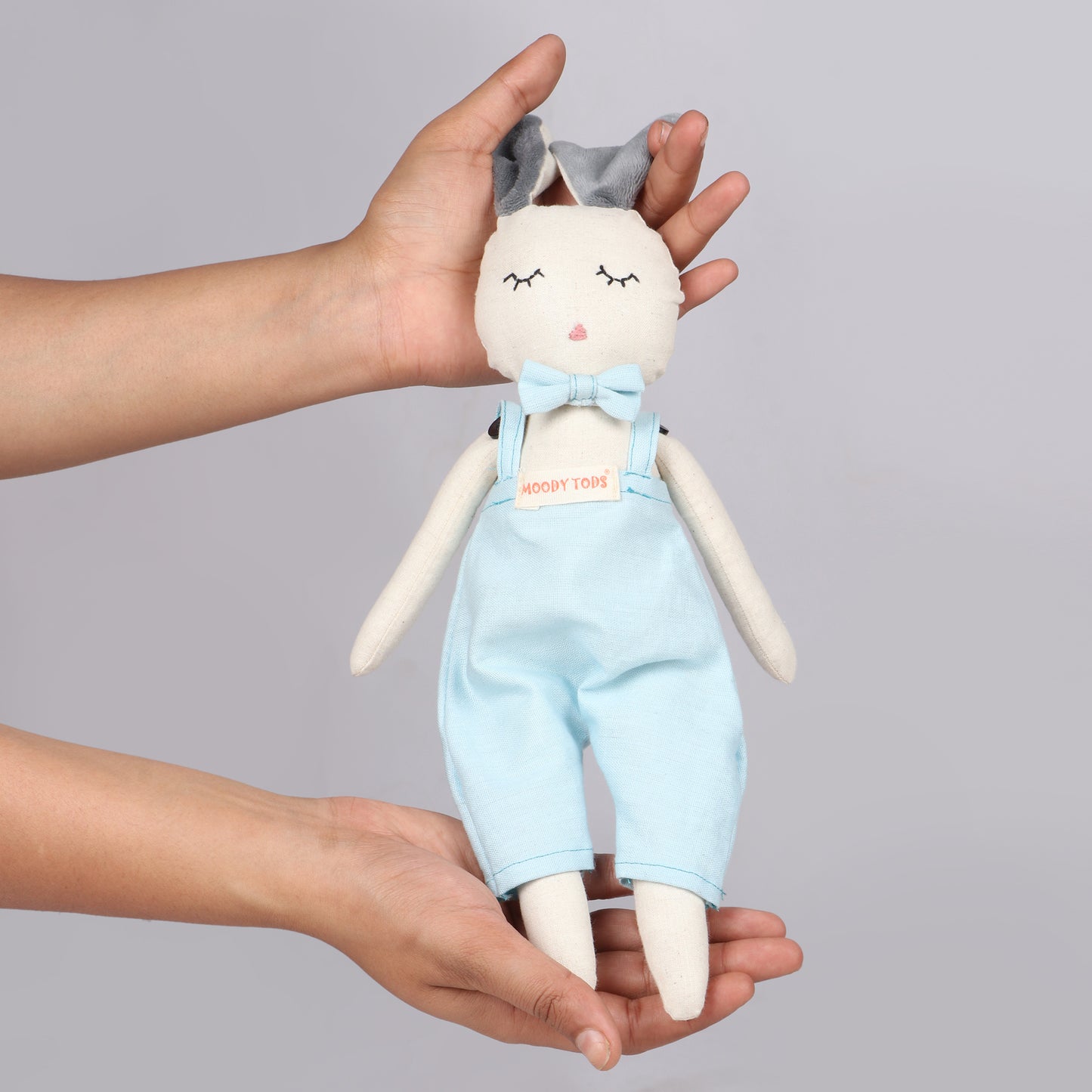 Holding an adorable 12 inch plush bunny toy in hand with blue pastel colored outfit, perfect for cuddles and sensory play
