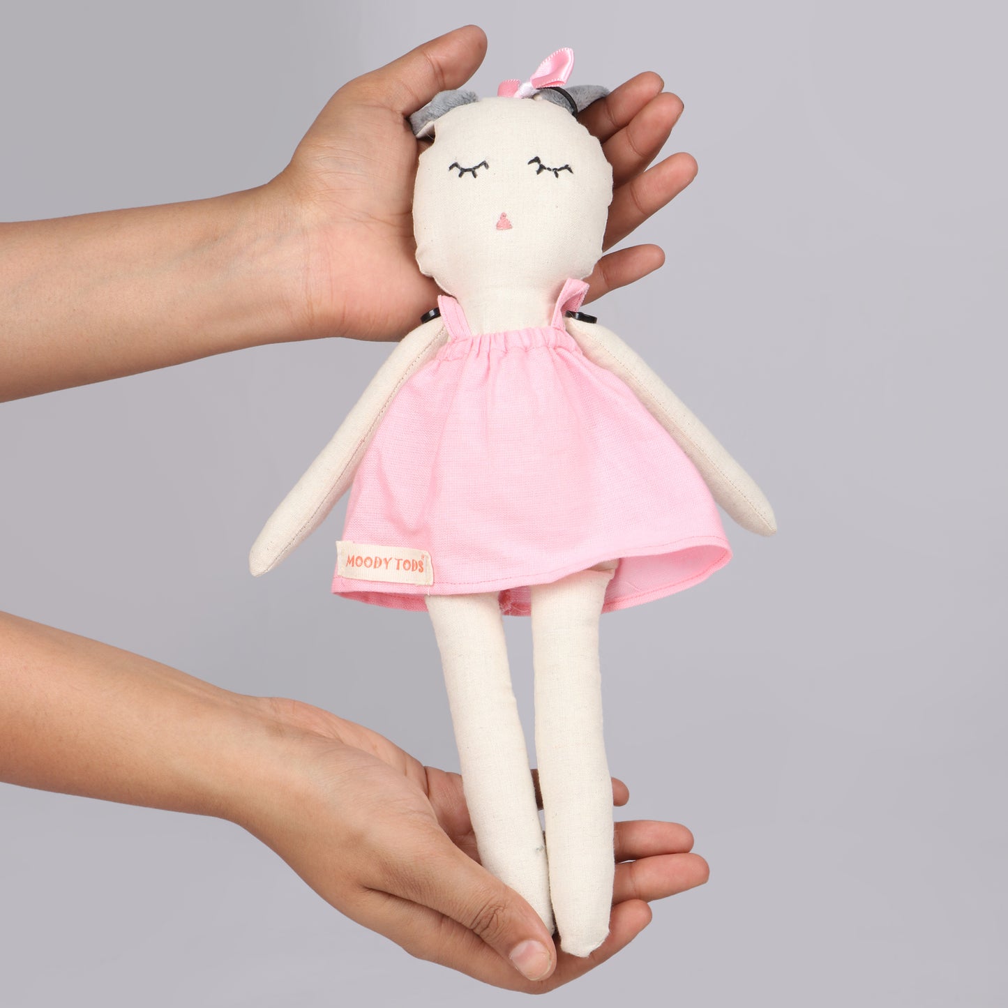 Holding an adorable 12 inch plush bunny toy with pink pastel colored outfit, perfect for cuddles and sensory play