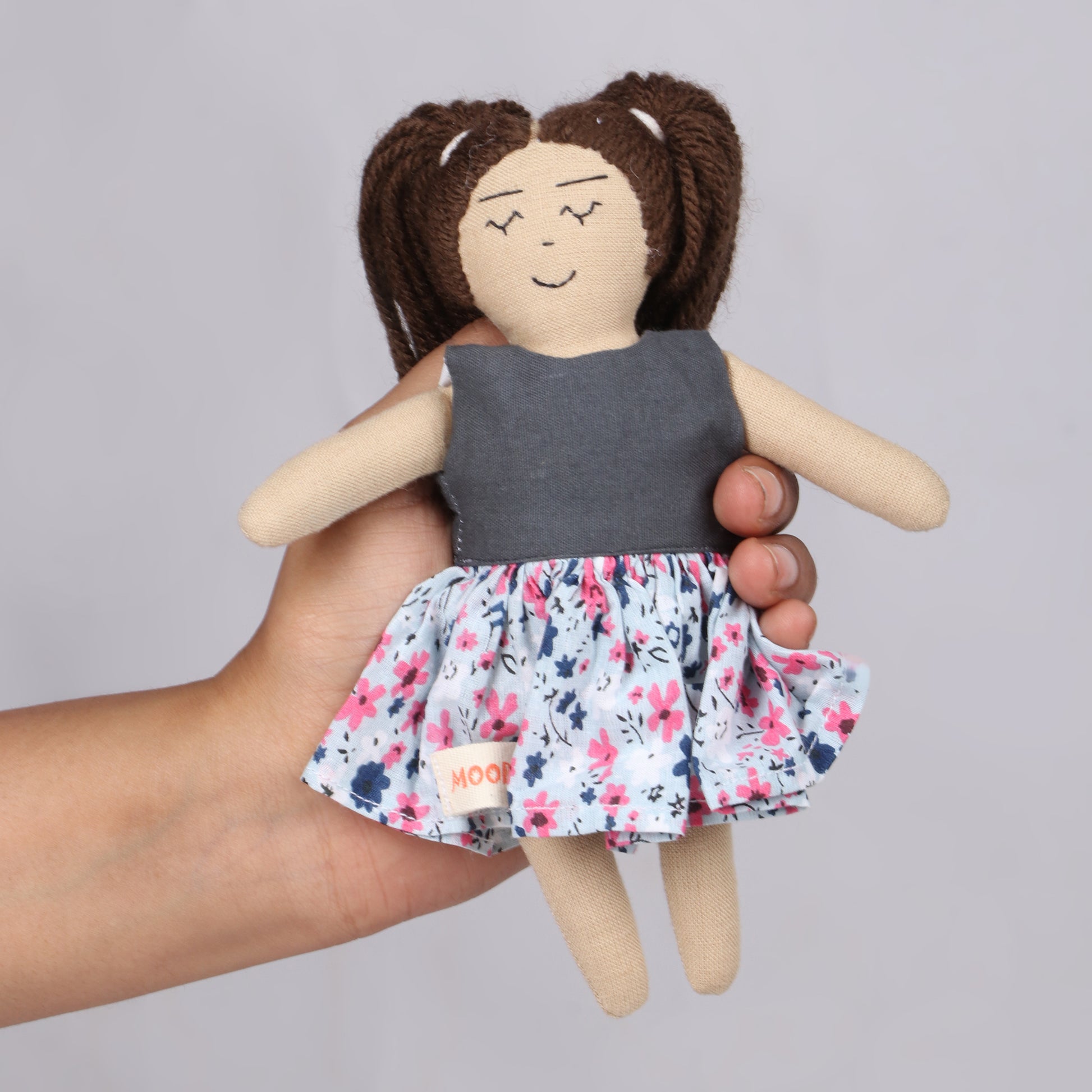Holding a cute 7 inch girl rag doll with gray color top and floral skirt, made from child-safe, soft fabric