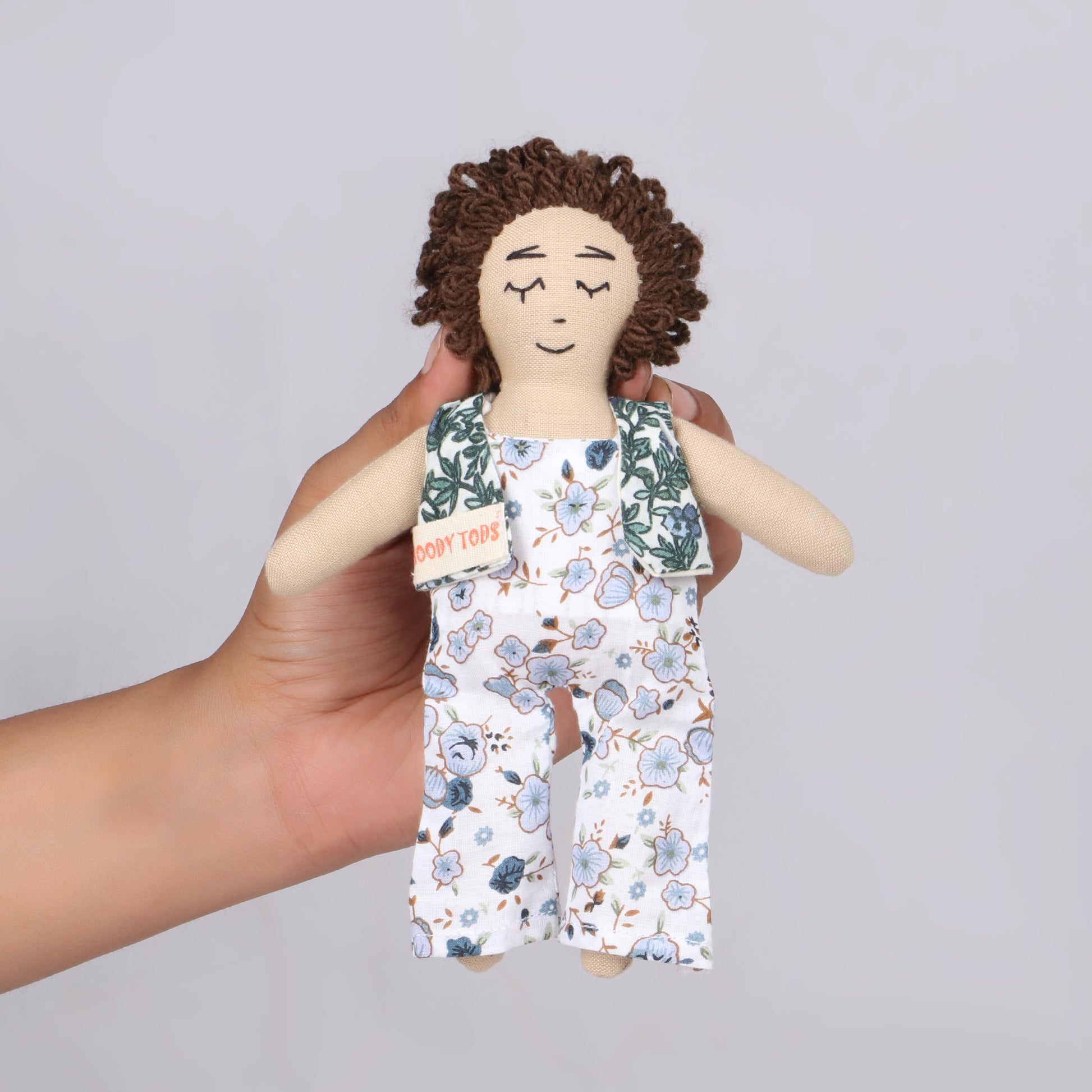 Holding cute 7 inch fabric boy rag doll demonstrating its size compared to average palm size
