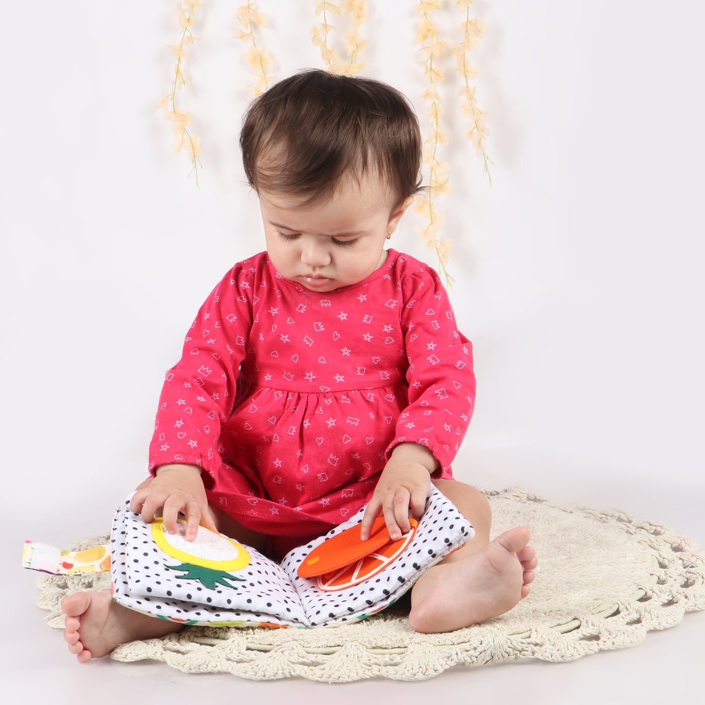 Toddler playing with fruit-themed bust book exploring its interactive elements, helping toddlers learn about colors, shapes and fruits
