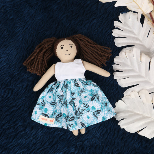 Front view of a 9 inch handmade fabric girl rag doll with embroidered facial features and a white floral outfit made from child-safe, soft fabric