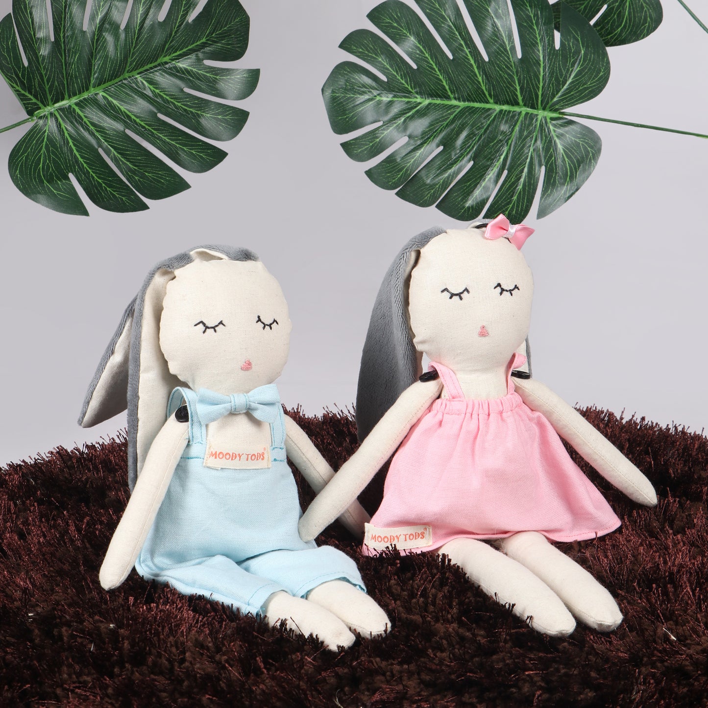 Pair of an adorable 12 inch plush bunny toys in sitting position with blue and pink pastel colored outfit, perfect for cuddles and sensory play