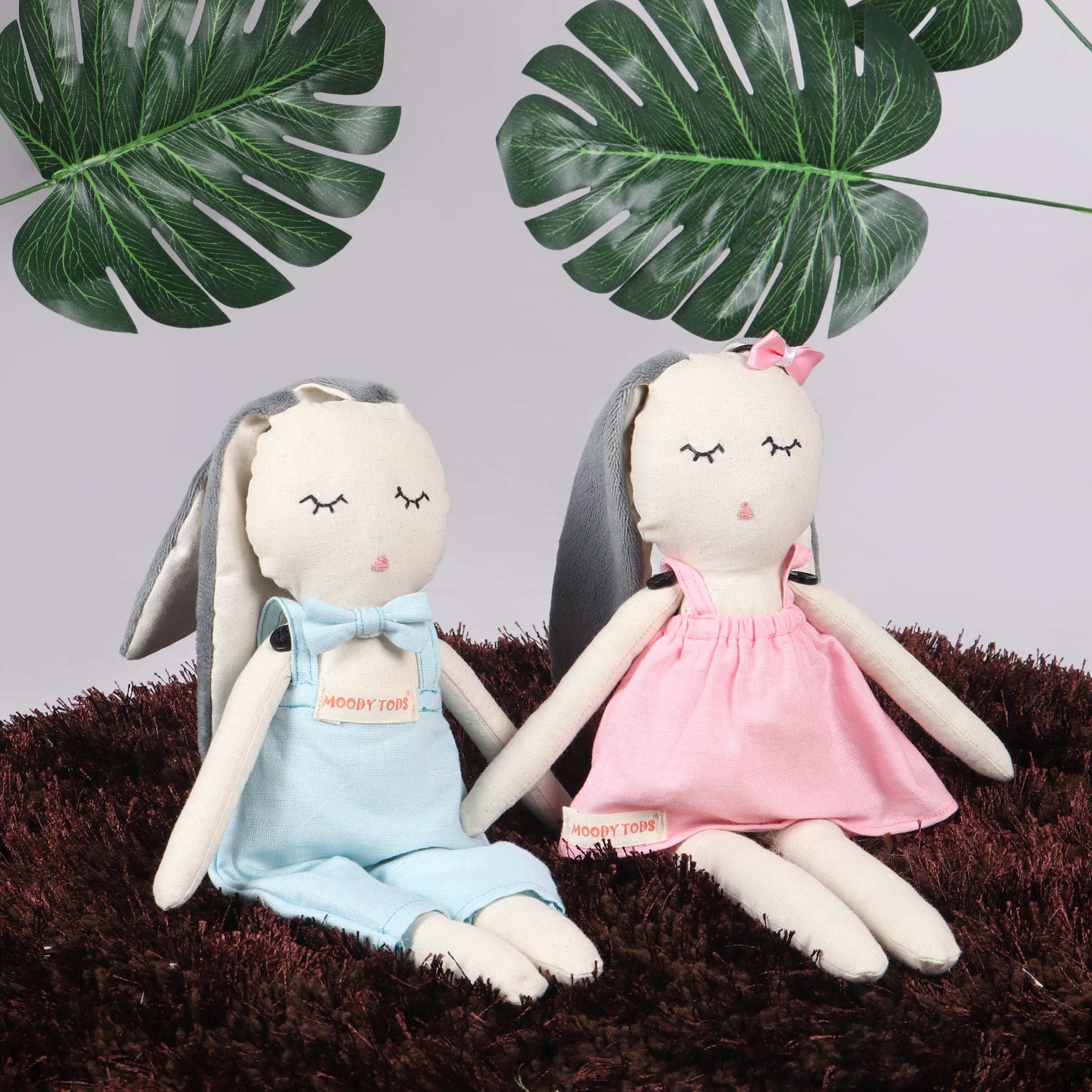 Pair of an adorable 12 inch plush bunny toys in sitting position with blue and pink pastel colored outfit, perfect for cuddles and sensory play