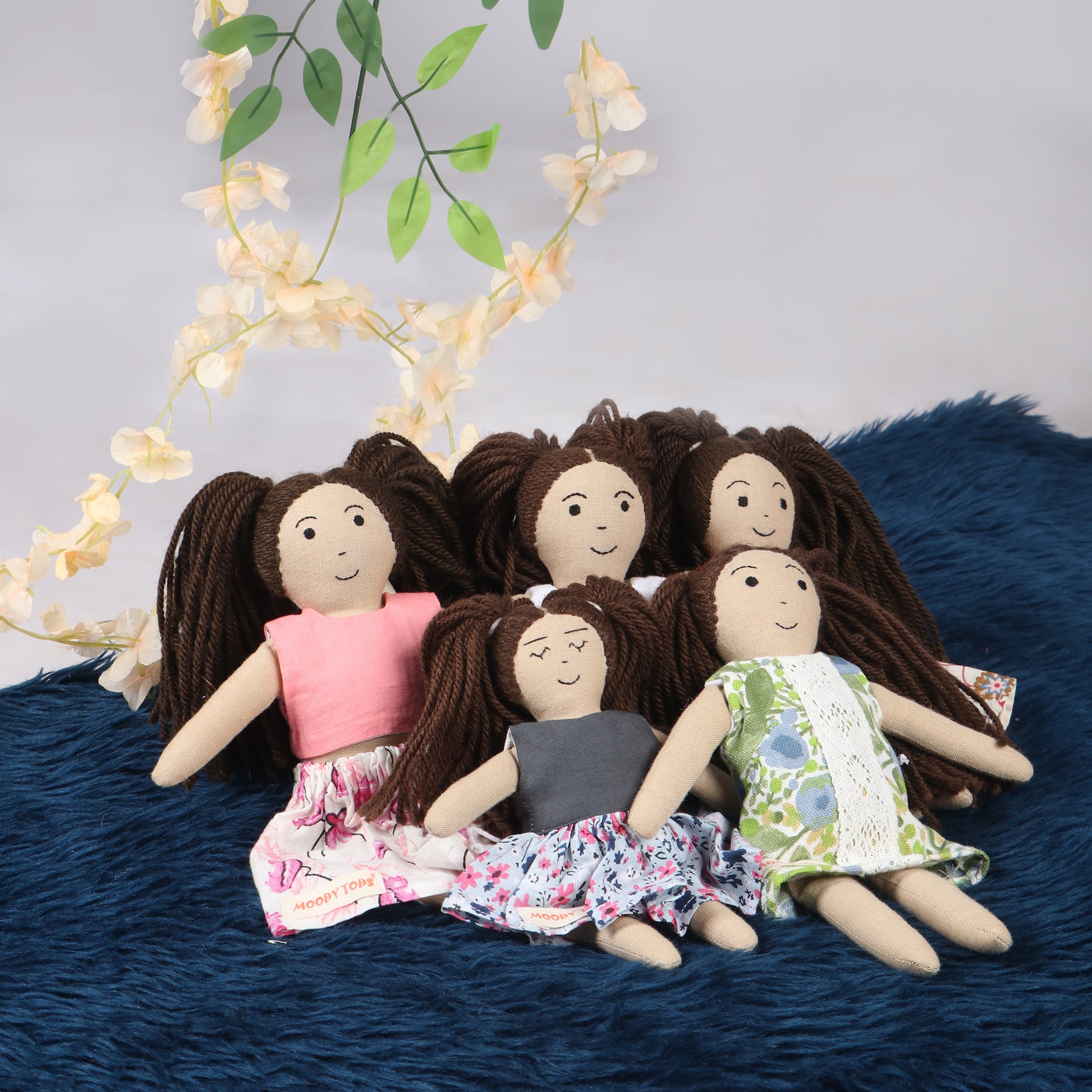 Side angle of cute 5 handmade fabric girl rag doll in sitting position with soft, sensory-friendly material