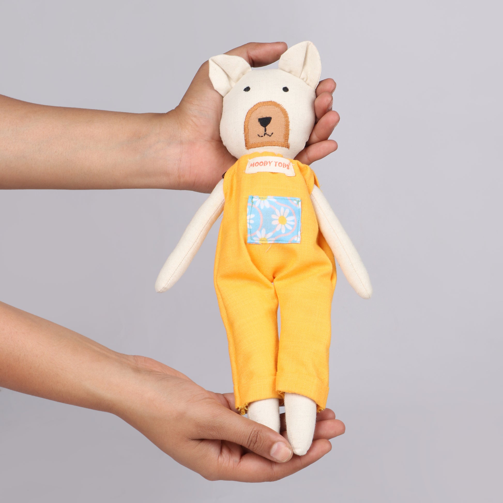 Holding a 12 inch soft fabric bear doll in hands wearing pastel orange colored outfit, ideal for toddlers and young children