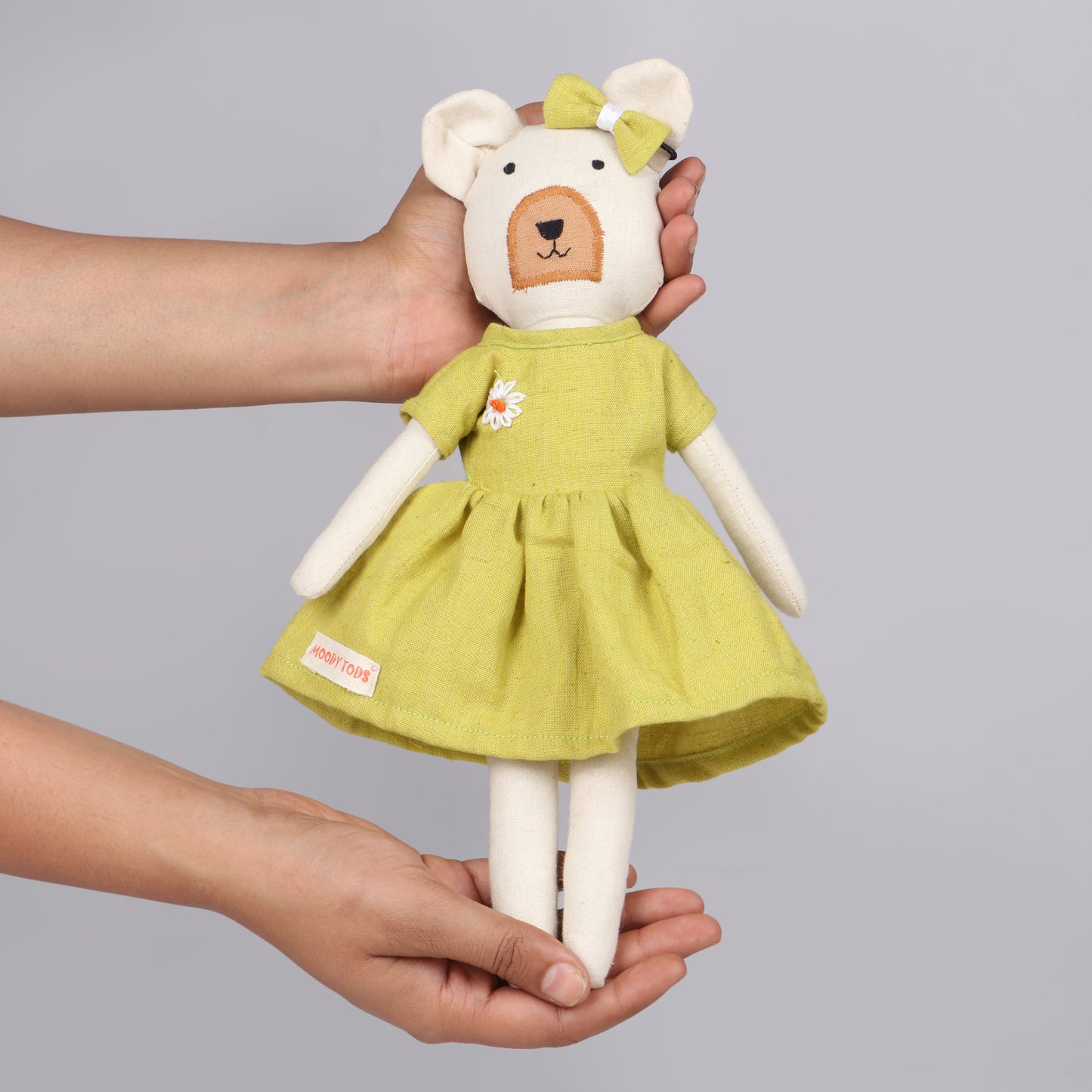 Holding a 12 inch soft fabric bear doll in hands with little hair clip and pastel green colored outfit, ideal for toddlers and young children